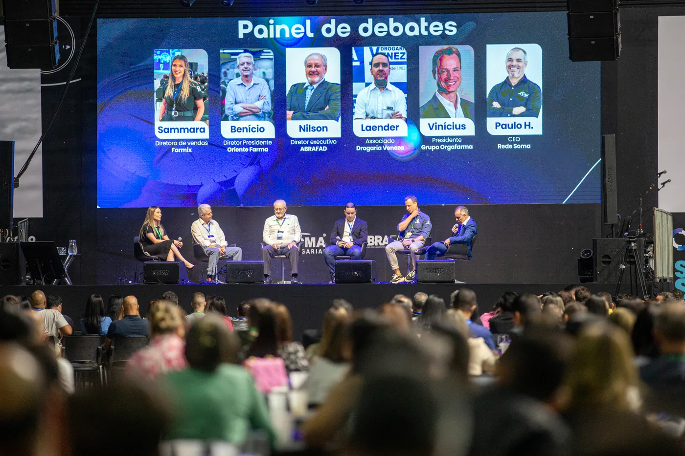 Painel de debates no palco principal, com plateia lotada