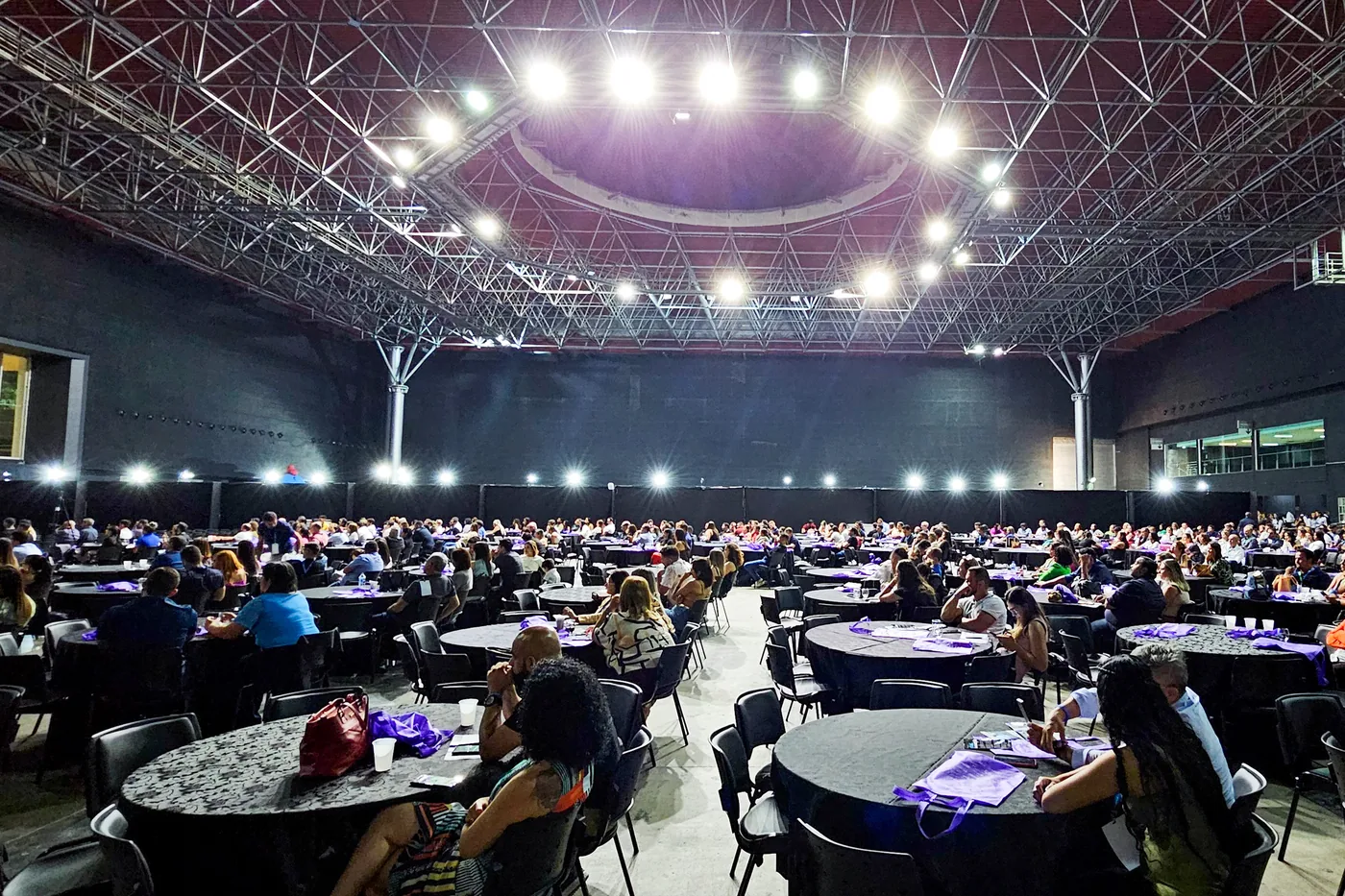 Salão de jantar com mesas ocupadas por participantes